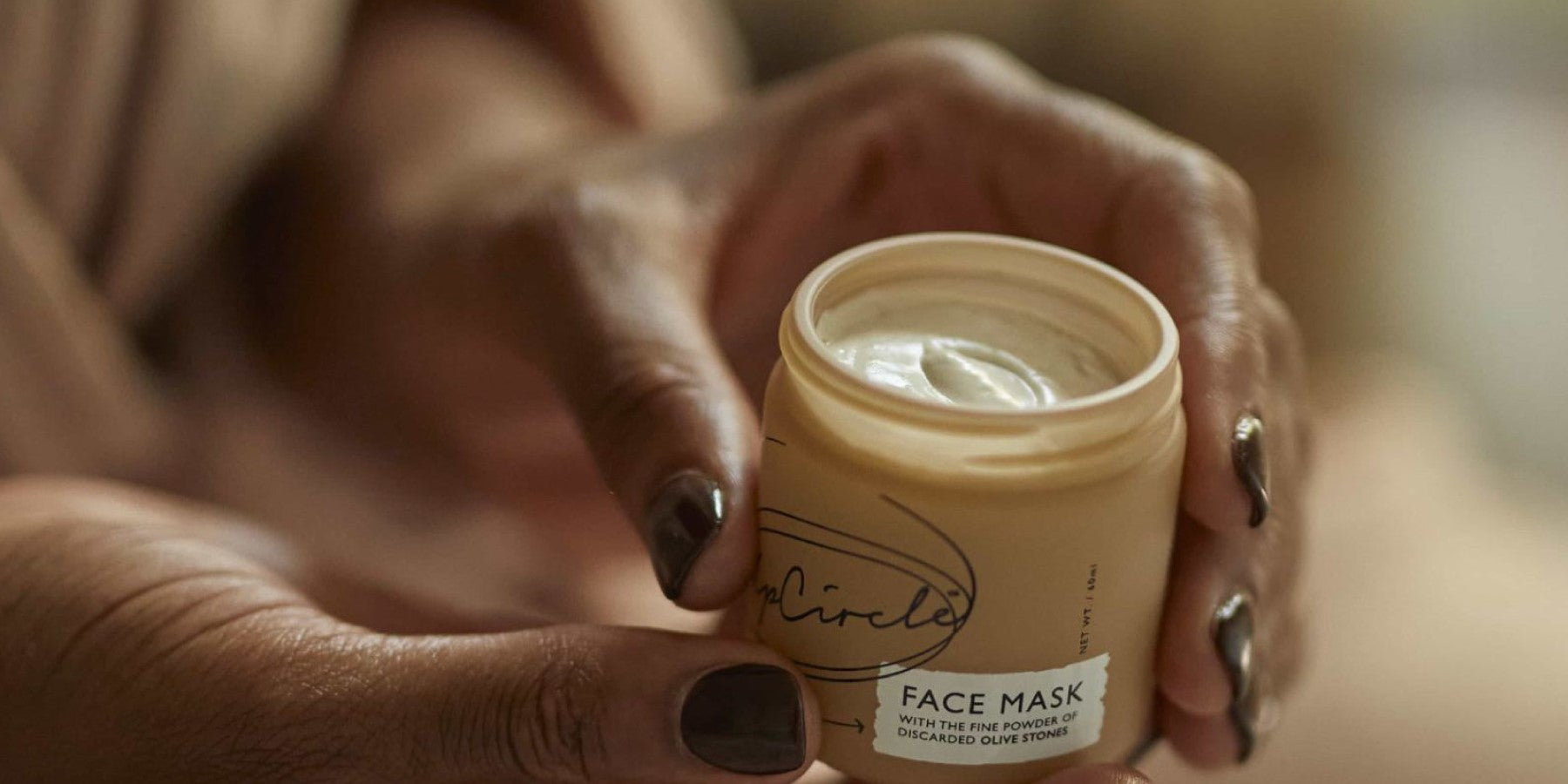 Vroue met potje UpCircle gezichtsmasker in haar handen